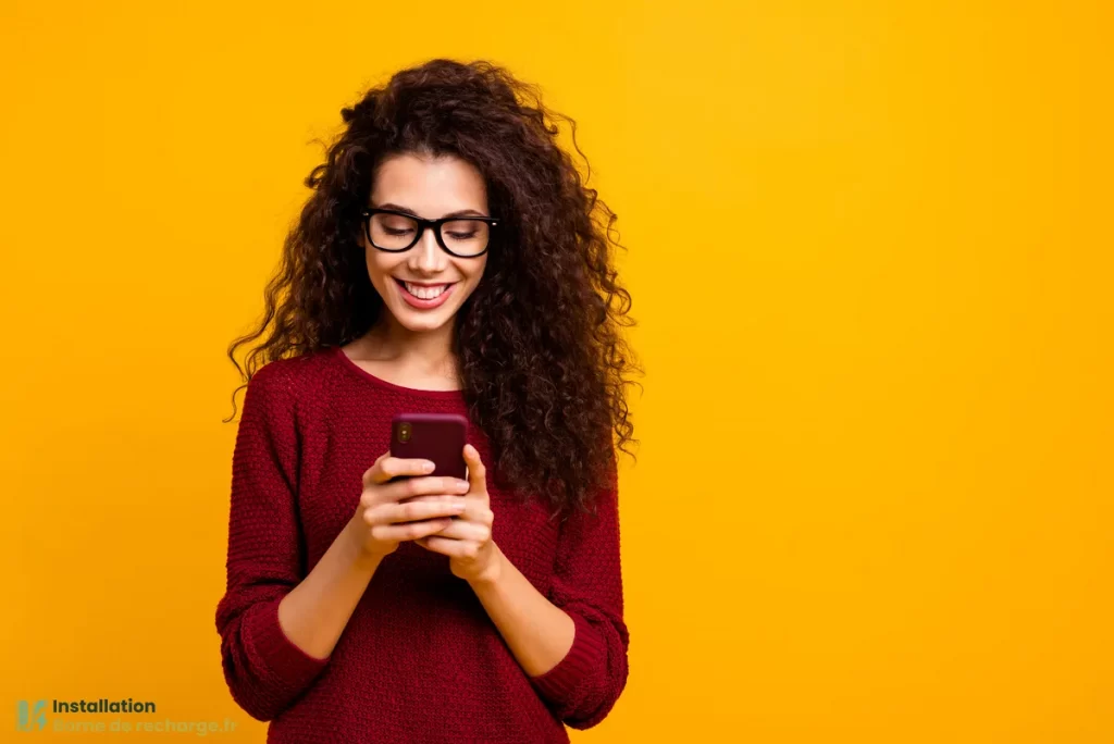 Une femme souriante regarde une application sur son smartphone.